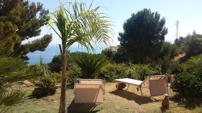 a picnic table and a palm tree in a garden at Agave Scopello in Scopello