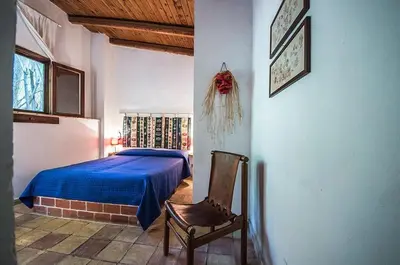 a bedroom with a blue bed and a chair at Casa Ninfee, immersa nel verde con piscina in comune in Terrasini