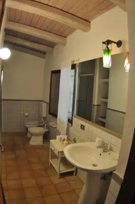 a bathroom with two sinks and a toilet and a mirror at Casa Ninfee, immersa nel verde con piscina in comune in Terrasini