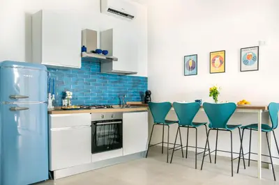 a kitchen with a refrigerator and a table with stools at Colonna Secret, Private Jacuzzi in Historic Center in Palermo