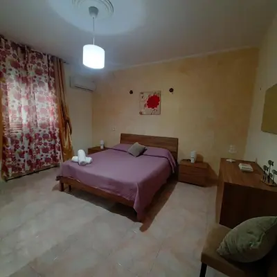 a bedroom with a purple bed and a couch at Maria Isabella appartament in Isola delle Femmine