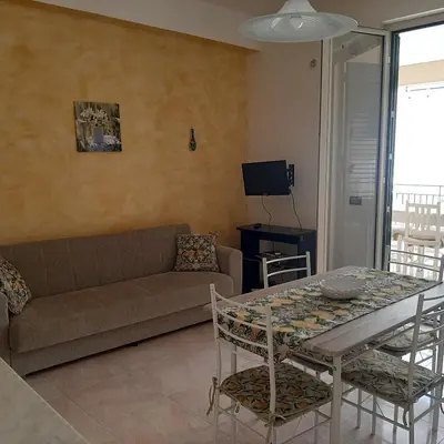 a living room with a couch and a table and chairs at Maria Isabella appartament in Isola delle Femmine