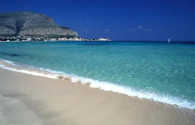 a beach with the ocean and a mountain in the background at Ashur Mondello, sapore di sale in Palermo