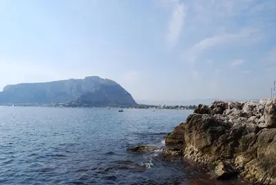 a large body of water with a mountain in the background at Ashur Mondello, sapore di sale in Palermo