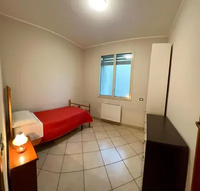 a small bedroom with a red bed and a window at West Sicily Beach in Balestrate