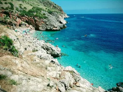 a group of people swimming in the blue ocean at West Sicily Beach in Balestrate