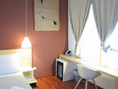 a bedroom with a bed and a desk and a window at Bio Hotel Palermo in Palermo