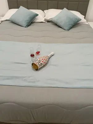 a bed with a bottle and two glasses on it at Wellness House in Bagheria