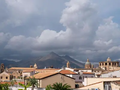 a city with buildings and a mountain in the background at Locanda Lupo in Palermo