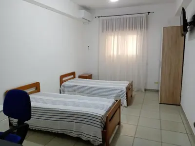 a room with two beds and a chair and a window at Casa Montalbano in Nuova Gibellina