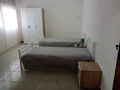 a bedroom with two beds and a table and a cabinet at Casa Montalbano in Nuova Gibellina