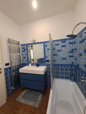 a blue tiled bathroom with a sink and a tub at Emily's Place in Palermo