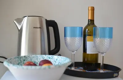 a bottle of wine next to two glasses and a bowl of fruit at Maioliche Rooms in Campofelice di Roccella