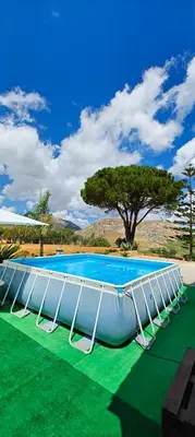 a swimming pool with white chairs on a green field at Villa Calatafimi Segesta in Calatafimi