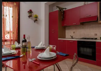 a kitchen with red cabinets and a red table with chairs at Indipendente a S vito lo Capo in San Vito lo Capo
