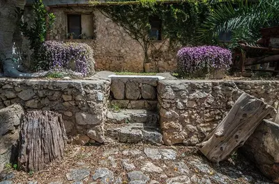 a stone wall with purple flowers in front of a building at Casa Laghetto in the countryside with a shared pool in Terrasini