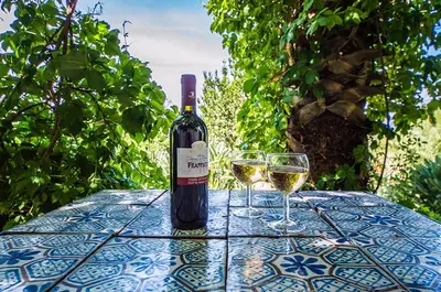 a bottle of wine sitting on a table with two glasses at Casa Laghetto in the countryside with a shared pool in Terrasini