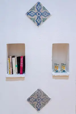 a white wall with three shelves with books at Casa Laghetto in the countryside with a shared pool in Terrasini