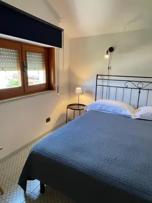 a bedroom with a bed with a blue comforter and two windows at Casetta Ciurì in Terrasini