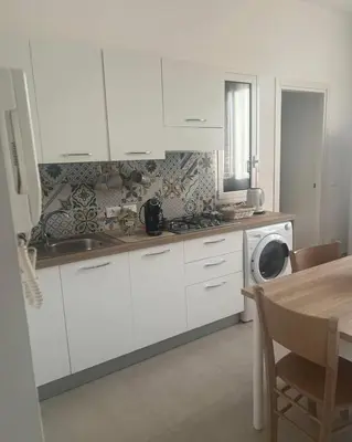 a kitchen with white cabinets and a washing machine at Palermo Sunhouse in Palermo