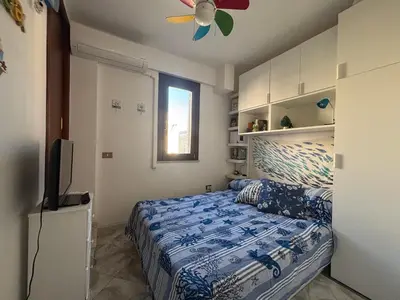 a bedroom with a bed and a ceiling fan at Sumarè in Isola delle Femmine