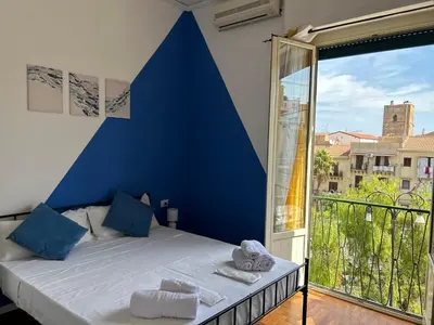 a bedroom with a blue wall and a large window at Balhara Floridi House in Palermo