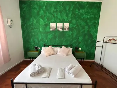 a bedroom with a bed with a green wall at Balhara Floridi House in Palermo