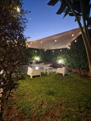a patio with a table and chairs in a yard at night at Villa indipendente con piscina in Terrasini