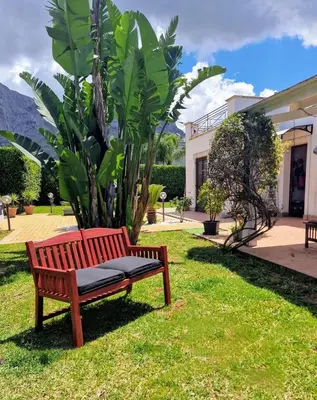 a wooden bench sitting in the grass next to a house at Villa indipendente con piscina in Terrasini