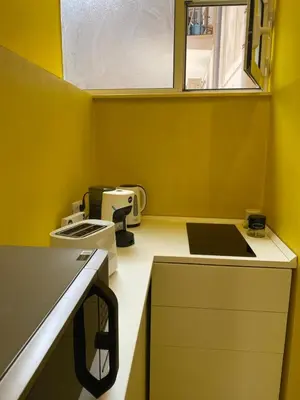 a small yellow kitchen with a sink and a microwave at Sunny Apartament in Palermo