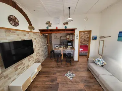 a living room with a couch and a television on a brick wall at marino casa vacanze in Carini