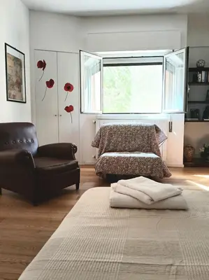 a bedroom with a bed and a couch and a window at una casa tranquilla in Palermo
