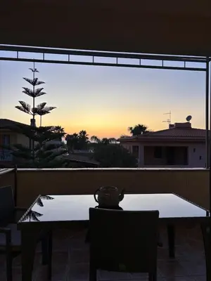a table and chairs on a balcony with the sunset at Villa Irene in Isola delle Femmine