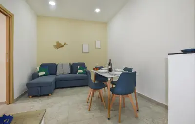 a living room with a blue couch and a table and chairs at Lovely Home In Isola Delle Femmine With Wifi in Isola delle Femmine