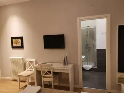 a living room with a table and a television on the wall at B&B Museo Salinas in Palermo