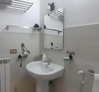 a white bathroom with a sink and a mirror at Borgo Vivo in Palermo