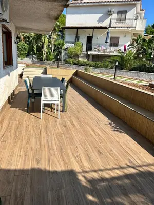 a patio with a table and chairs on a wooden deck at Via dei mirtilli in Carini
