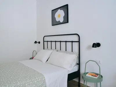 a bedroom with a bed with white sheets and a table at La casa di giù in Palermo