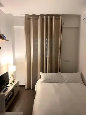a bedroom with a bed and a television and curtains at Nuovo appartamento sul mare immerso nel verde in Palermo
