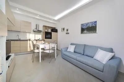 a living room with a blue couch and a kitchen at Case Della Baia in Castellammare del Golfo