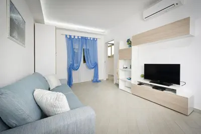 a living room with a blue couch and a television at Case Della Baia in Castellammare del Golfo