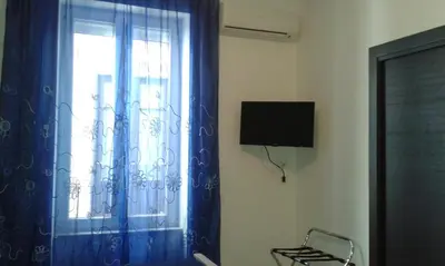 a room with a window with blue curtains and a chair at Buonaluna B&B in Palermo