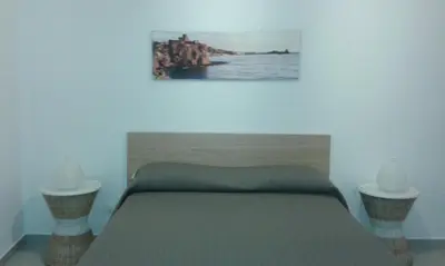 a bedroom with a bed with two nightstands and a painting at Buonaluna B&B in Palermo
