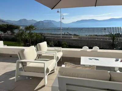 a patio with a couch and chairs and an umbrella at Palermo sul mare di Isola delle Femmine in Isola delle Femmine
