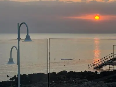 a sunset over the ocean with a boat in the water at Palermo sul mare di Isola delle Femmine in Isola delle Femmine