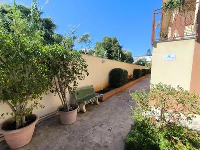 a green bench sitting next to a wall with trees at Azzurra Apartment Mondello - Casa Vacanza a due passi dal Mare in Palermo