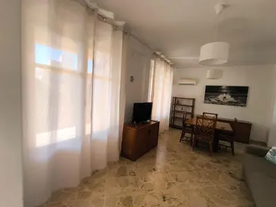 a living room with a television and a table with chairs at Azzurra Apartment Mondello - Casa Vacanza a due passi dal Mare in Palermo