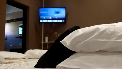 a bedroom with a bed with white sheets and a tv at Suite del Corso in Ficarazzi