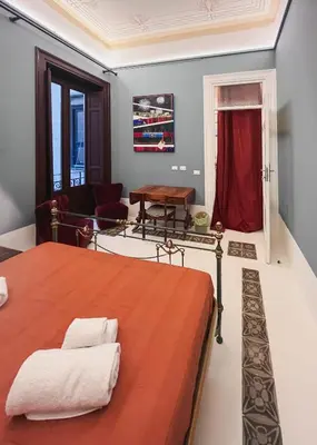 a bedroom with a bed and a living room at Galleria Cutò - Art Boutique Rooms in Palermo