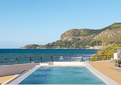 a swimming pool on the side of a house with the ocean at Solemar Sicilia - Villa Gloria in Ficarazzi